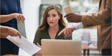 Worried young professional surrounded by people with documents